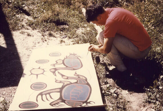 Norval Morrisseau painting outdoors,