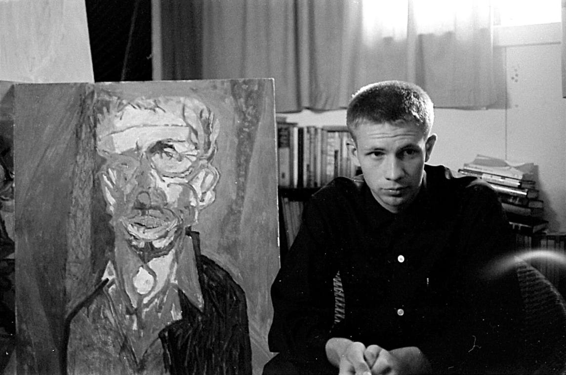 Art Canada Institute, Greg Curnoe, Greg Curnoe dans son premier atelier aménagé dans le sous-sol de sa maison d’enfance, à côté de son autoportrait Selfchildfool, 1959