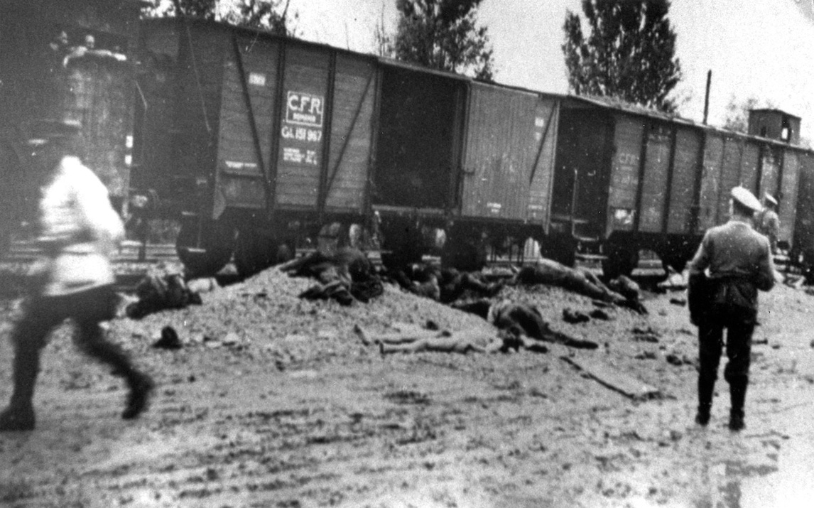 Romanian police walk past the bodies of Jews removed from the Iasi-Calarasi death train in Targu-Frumos, July 1, 1941