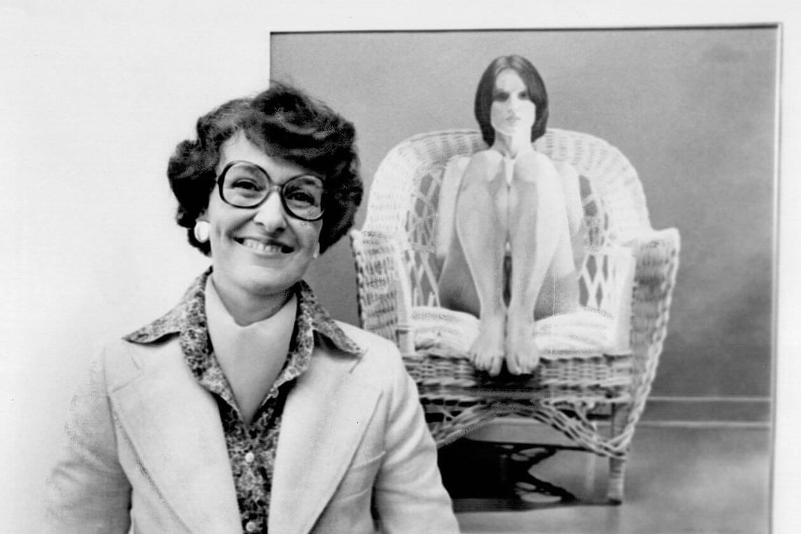 Mary Pratt standing beside her painting Girl in Wicker Chair shown at Aggregation Gallery, Toronto, 1978