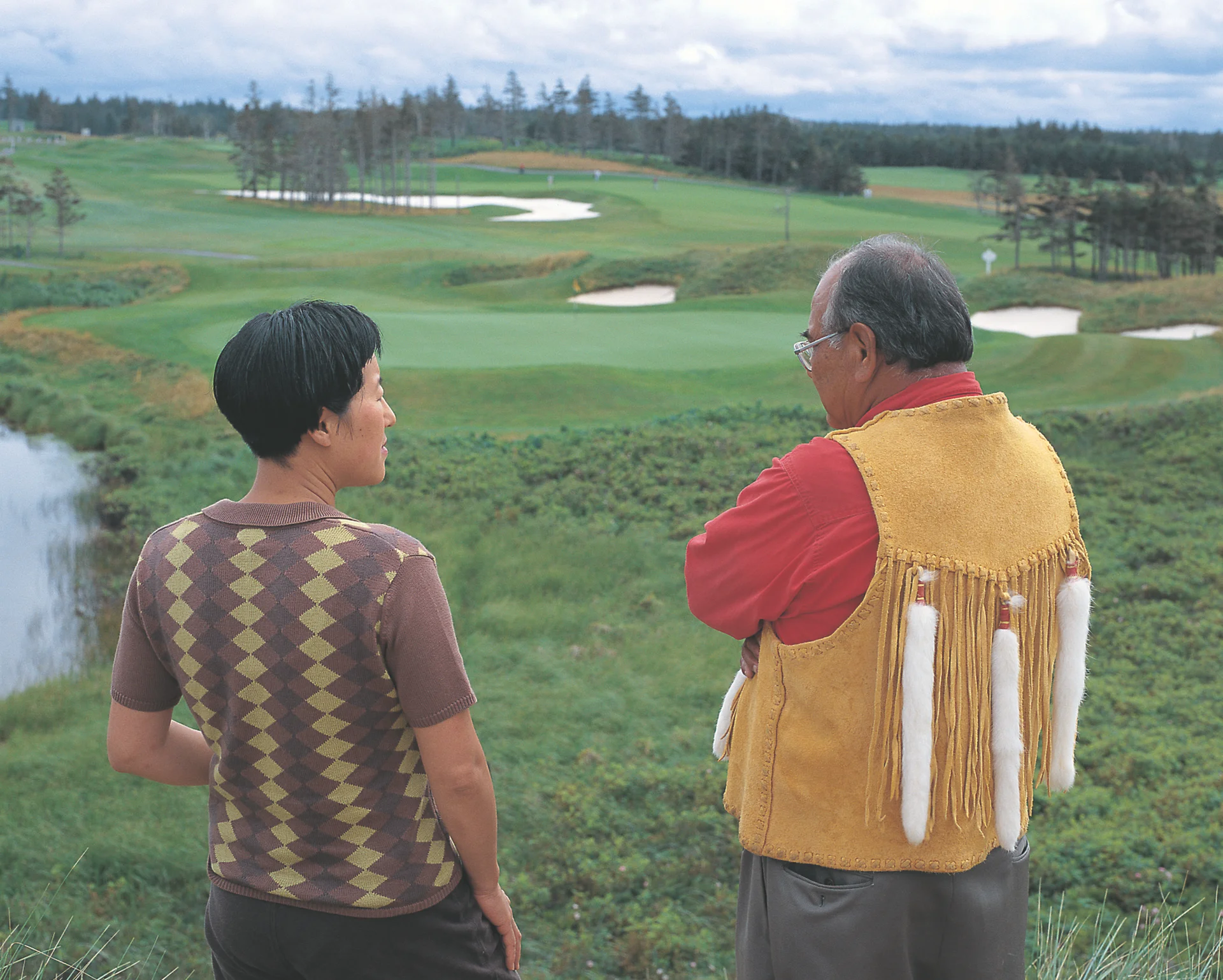 Two figures standing in front of a golf course with their backs to the camera