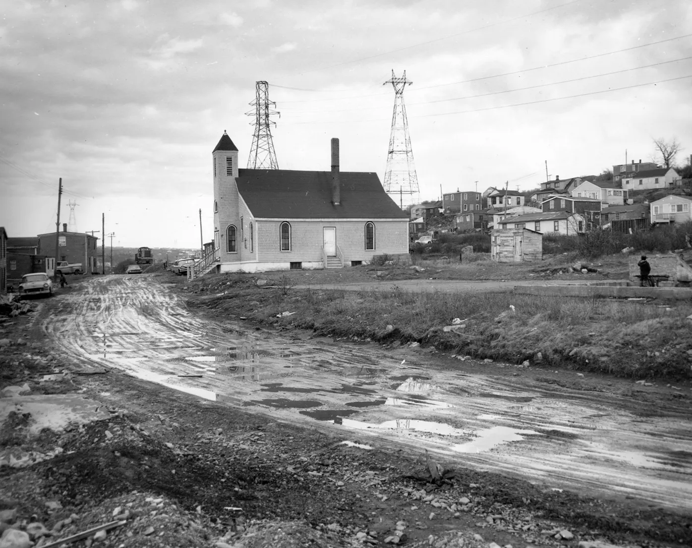 A black and white photo of a church and a dirt road